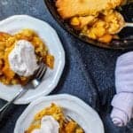 cornbread skillet peach cobbler in cast iron skillet with two servings on small plates