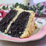 A slice of dark chocolate peanut butter layer cake on a dessert plate.