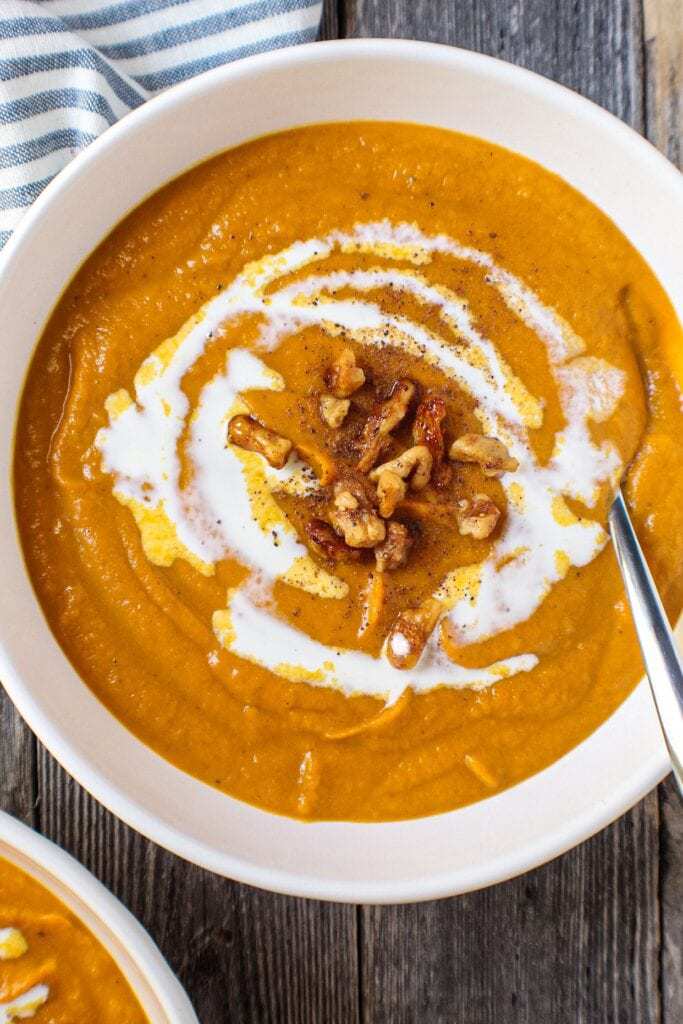 creamy sweet potato soup in white bowls topped with nuts