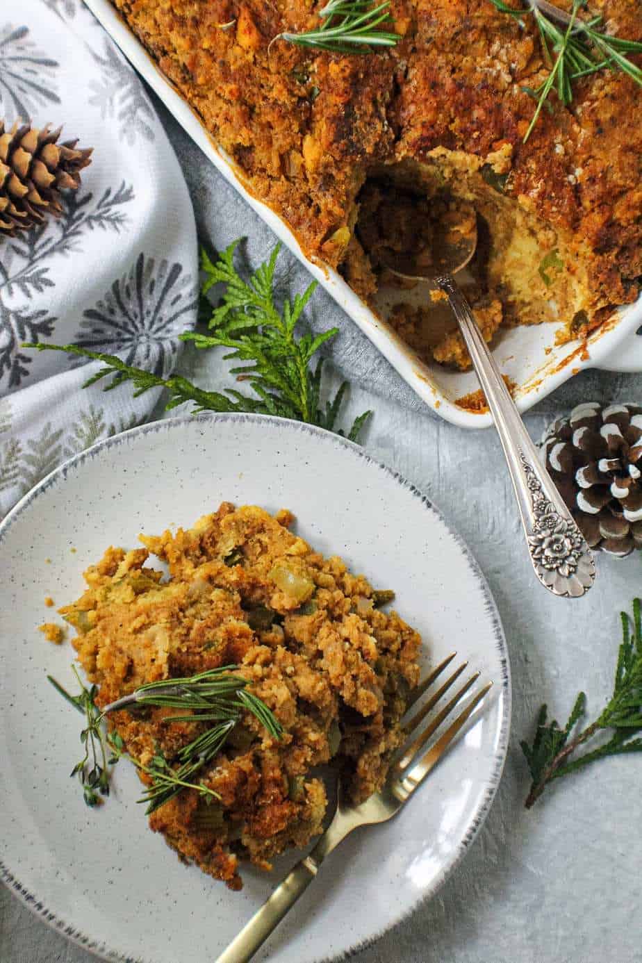 southern cornbread dressing on white plate topped with fresh herbs
