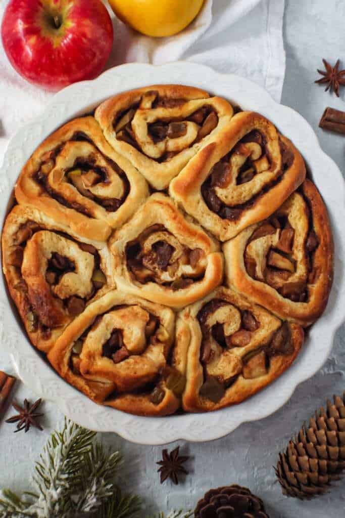 apple cinnamon rolls in a white pie dish before frosting.