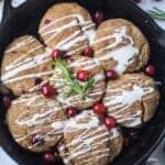 cranberry buttermilk biscuits topped with powdered sugar glaze in cast iron skillet garnished with fresh cranberries