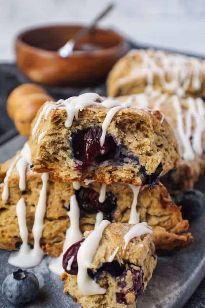 vegan blueberry scones with a powdered sugar glaze on a marble serving dish