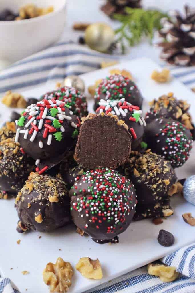 vegan dark chocolate truffles topped with chopped toasted walnuts on white plate with striped linen underneath plate