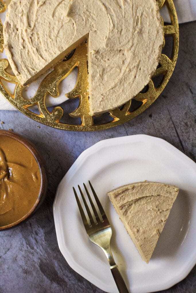 vegan peanut butter cheesecake on gold trivet with a slice of cheesecake on a small white plate with fork