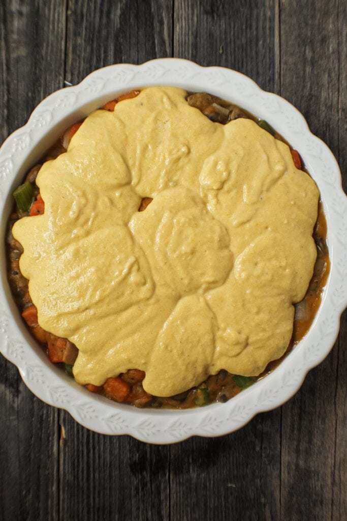 Cornbread Vegetable Pot Pie with cornbread batter on top before baking in the oven on top of wooden surface.