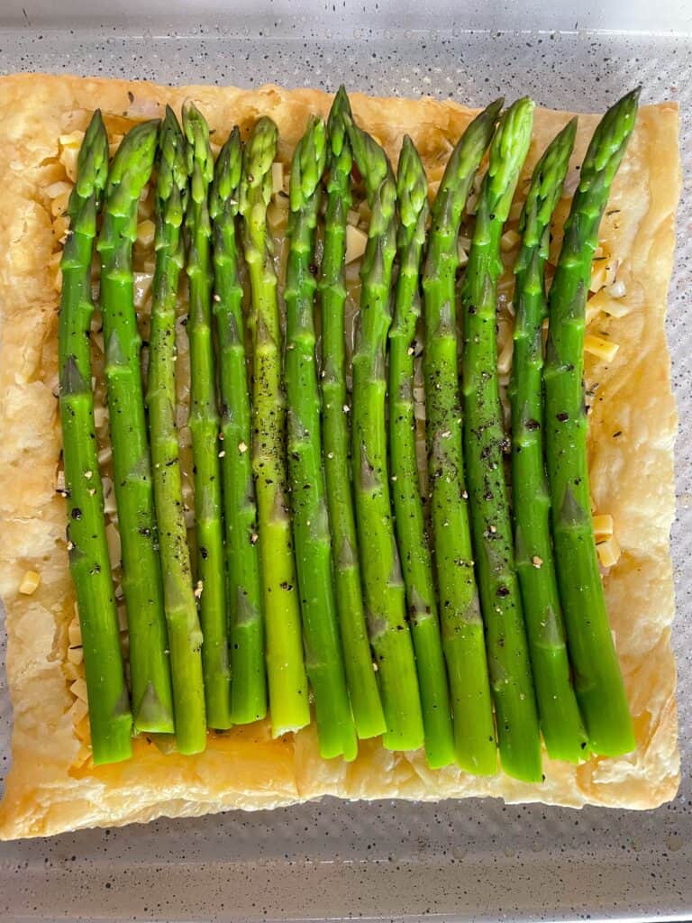 overhead shot of unbaked asparagus tart on parchment.