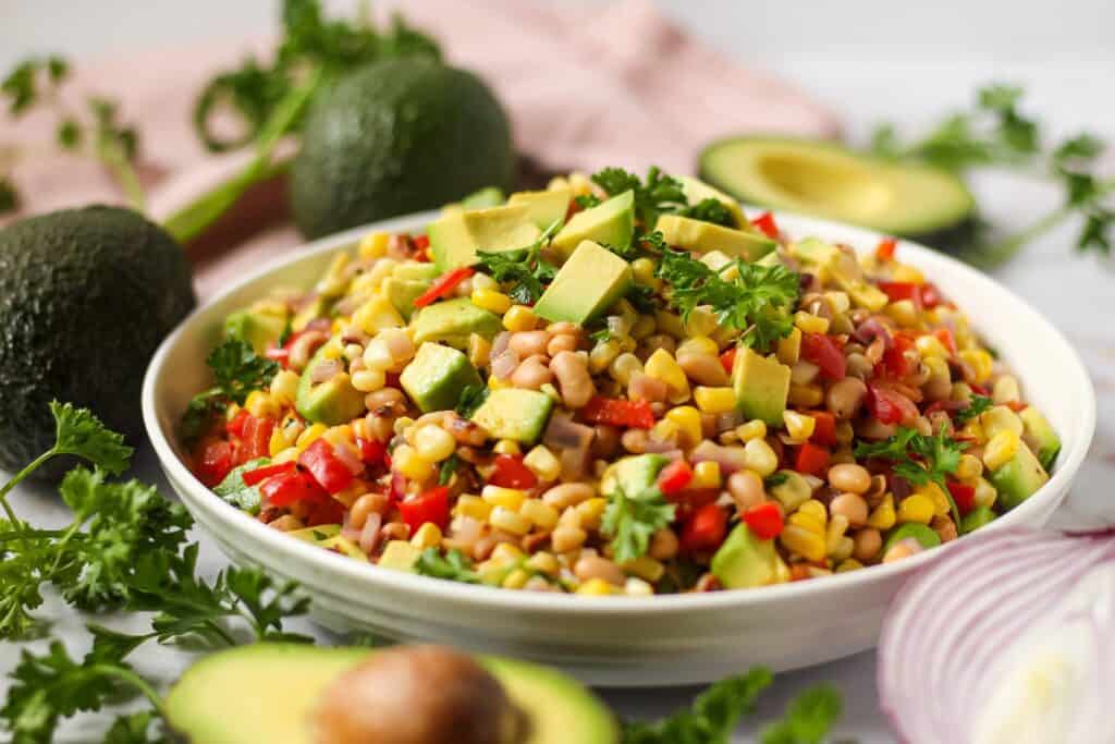 side angle shot of avocado and black-eyed pea succotash in white bowl