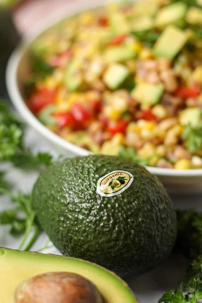 close up avocado with succotash in the background