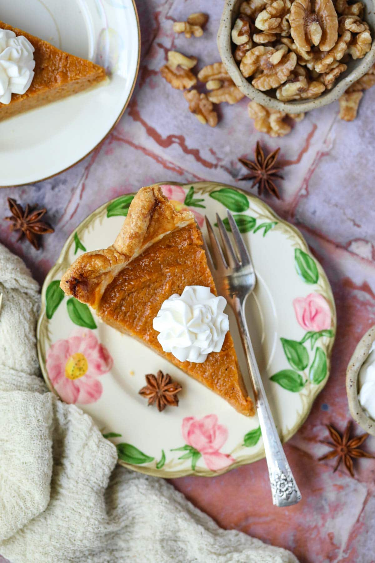 A slice of black folks southern sweet potato pie topped with fresh whipped cream on a dessert plate.