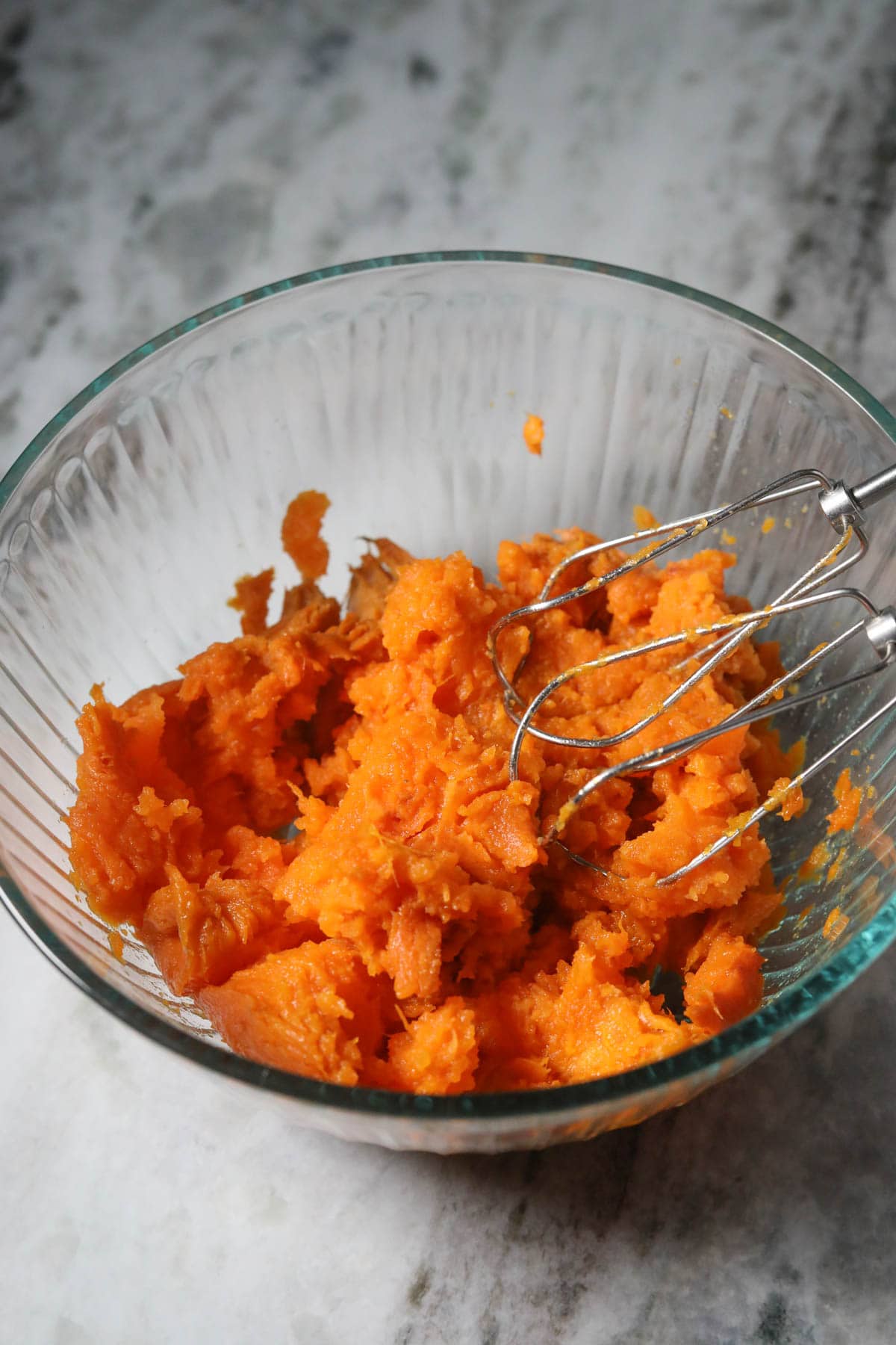 Roasted and mashed sweet potatoes in a mixing bowl.