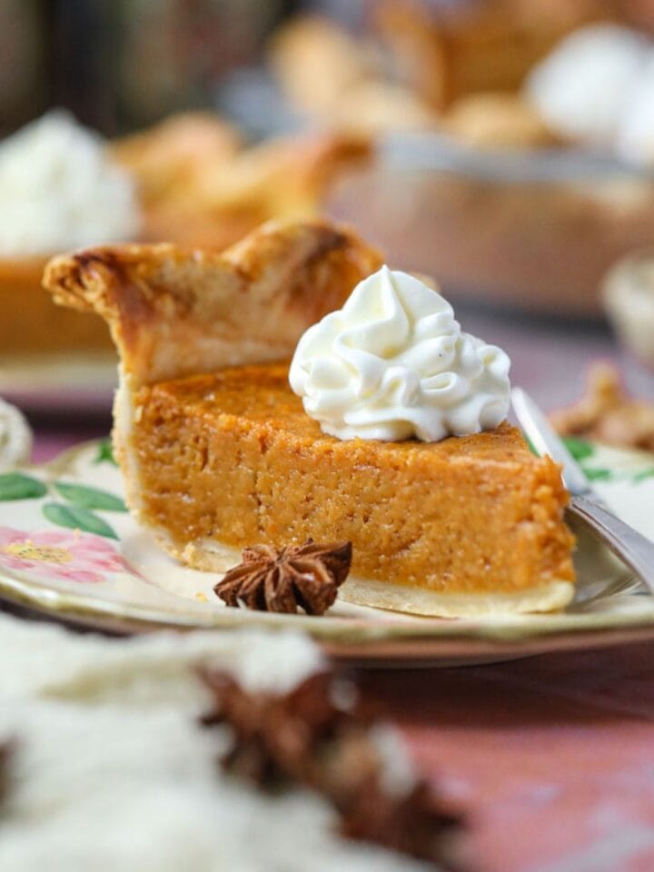 A slice of black folks southern sweet potato pie topped with fresh whipped cream on a dessert plate.