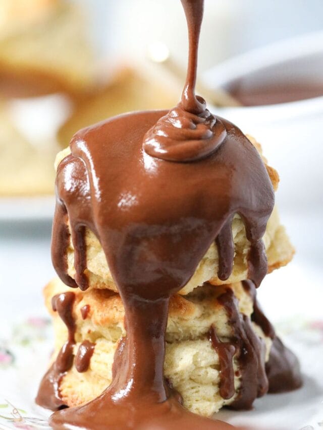 Chocolate gravy being poured over buttermilk biscuits.