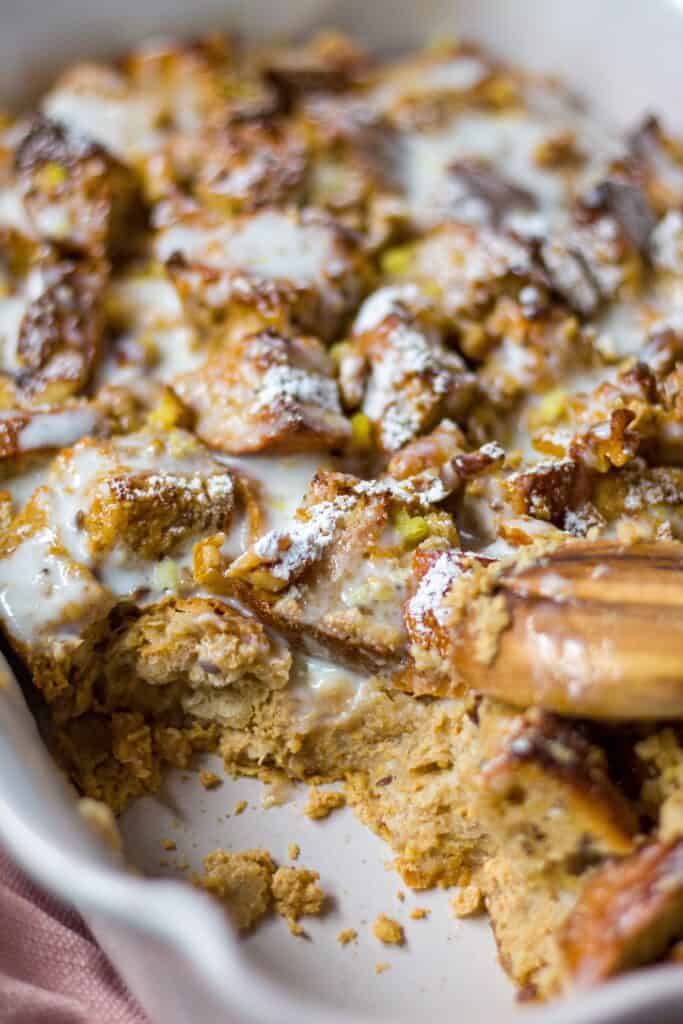 side shot of lemon bread pudding with lemon greek yogurt glaze with wooden spoon in shot