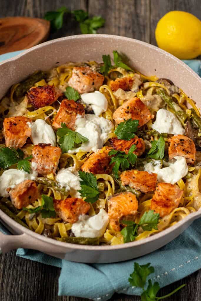 creamy salmon pasta in skillet on wooden surface