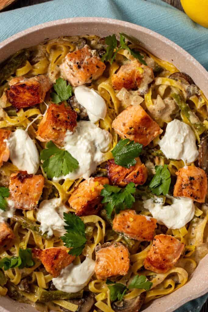 overhead shot of creamy salmon pasta in skillet with blue linen underneath