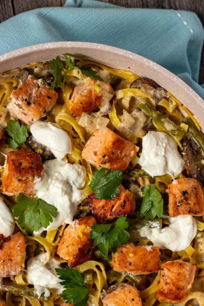 close up of salmon psta in skillet with blue linen underneath.