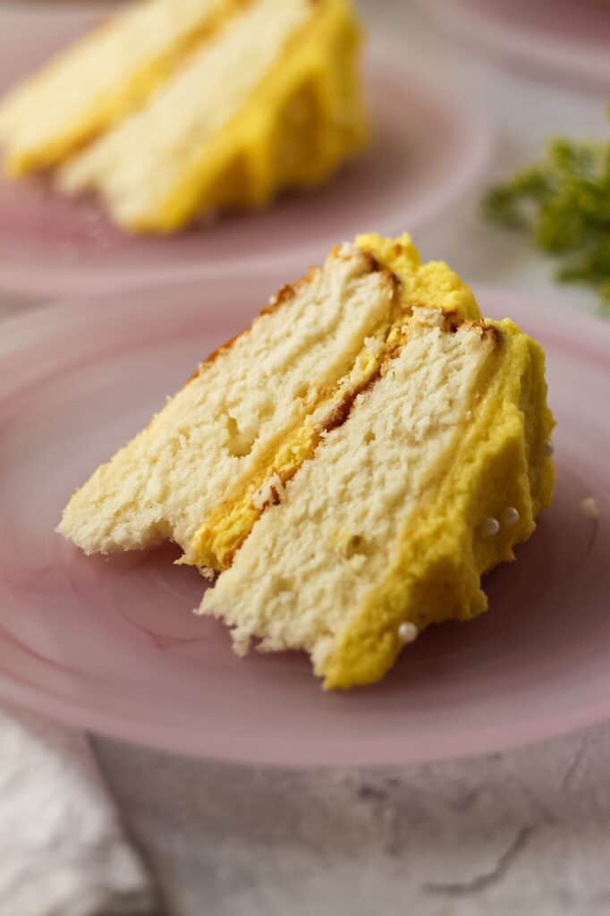 close up of slice of almond cake with lemon buttercream