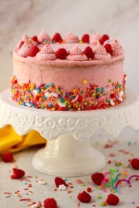 side shot of lemon raspberry birthady cake on white cake stand
