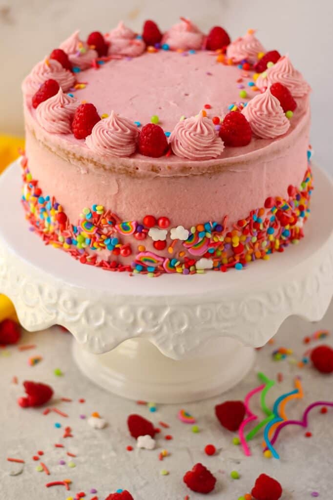 side shot of lemon raspberry birthday cake on white cake stand