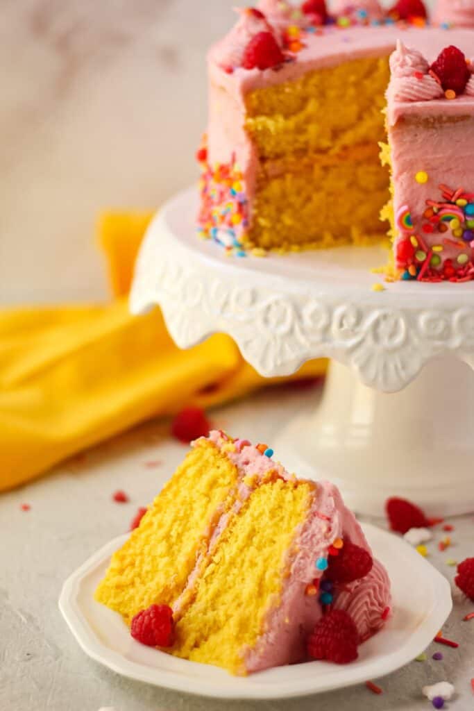 side shot of sliced lemon raspberry birthday cake on white plate