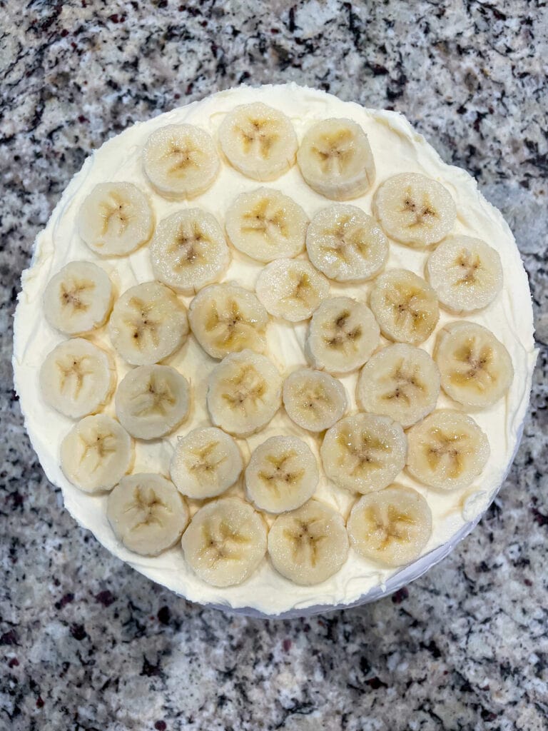 overhead shot of banana slice layer on top of banana icebox pie on granite countertop
