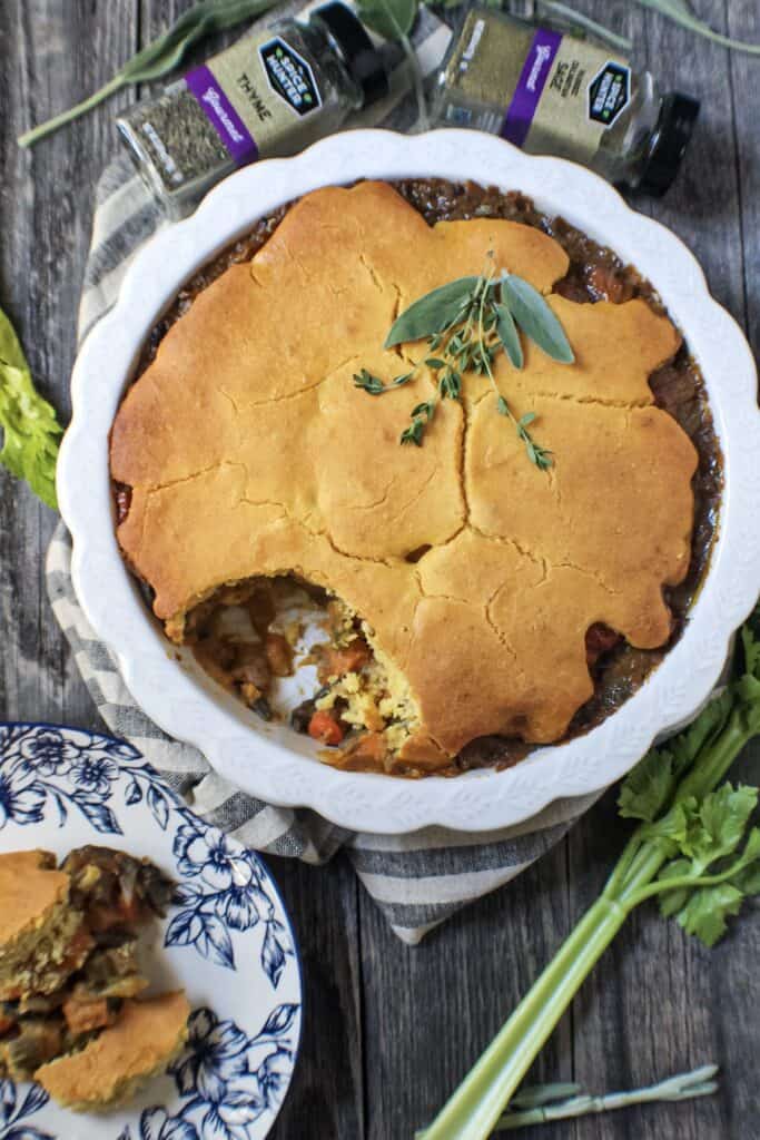 overhead shot of cornbread vegetable pot pie in glass pie dish on top of wooden surface