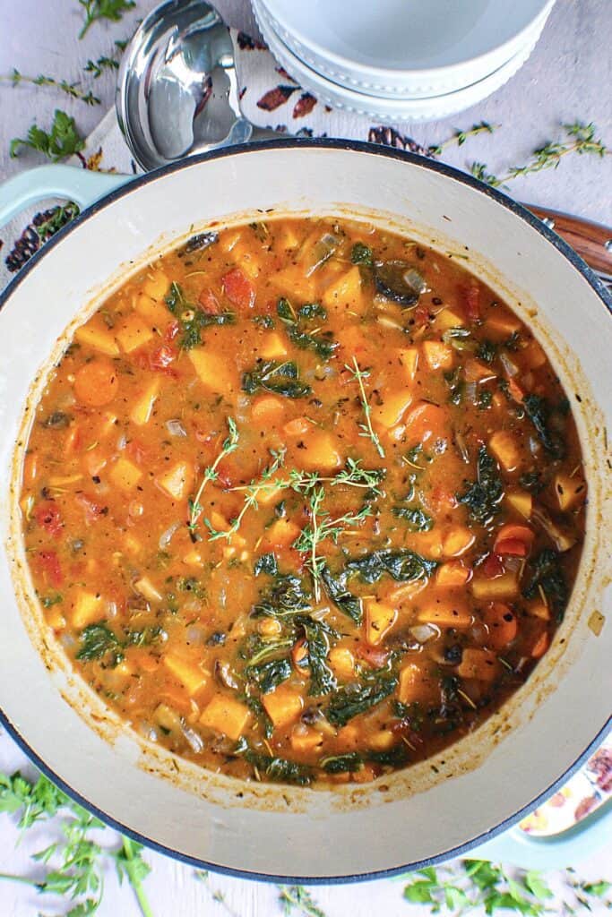 overhead shot of vegetable soup in dutch oven with ladle on the side of the pot.