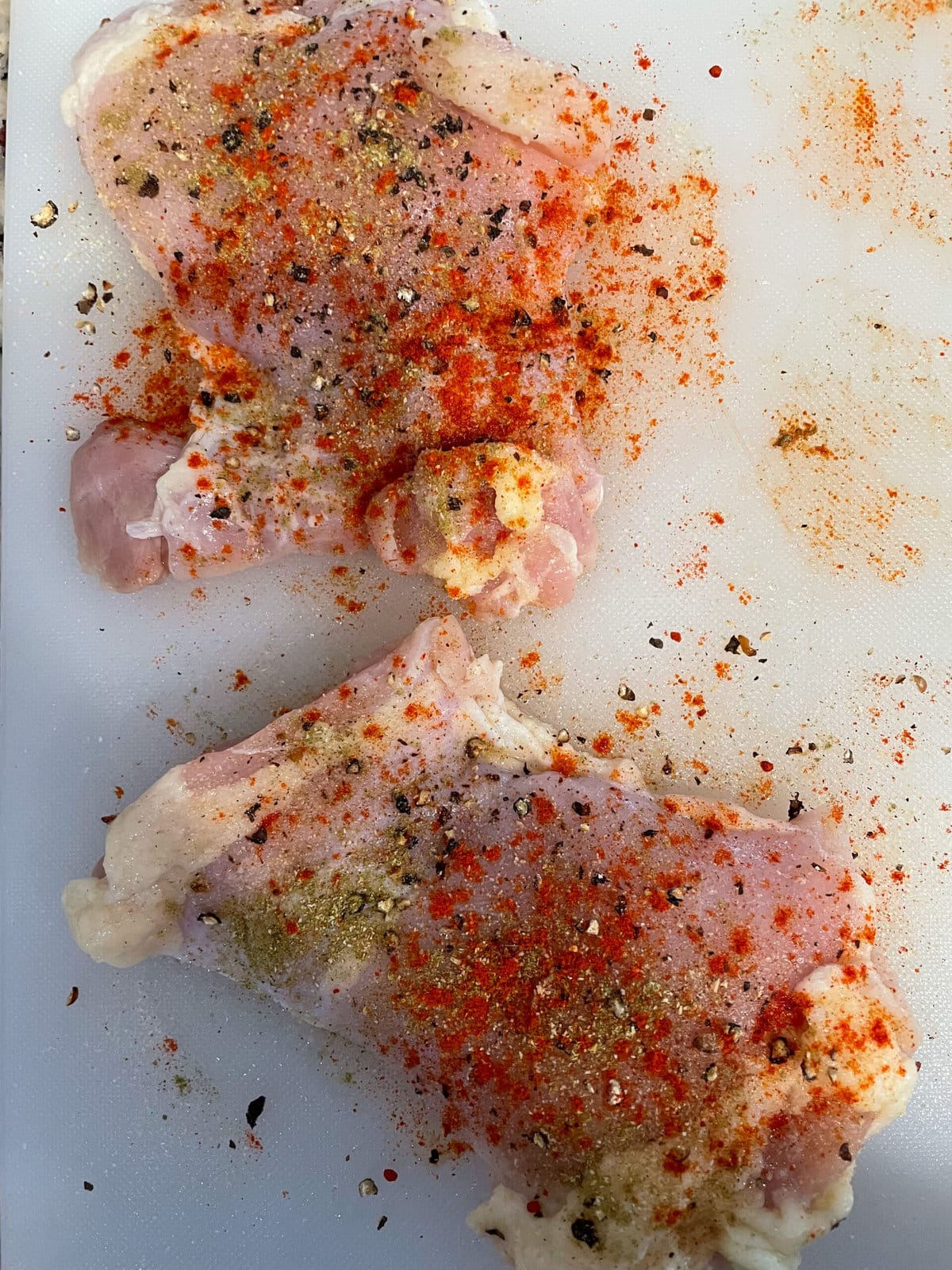 seasoned raw chicken thighs on cutting board