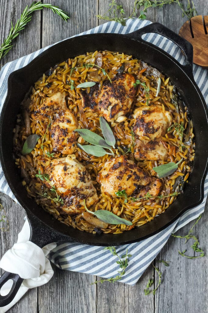 overhead shot of one pan sage butter chicken and orzo in a cast iron skillet on wooden surface