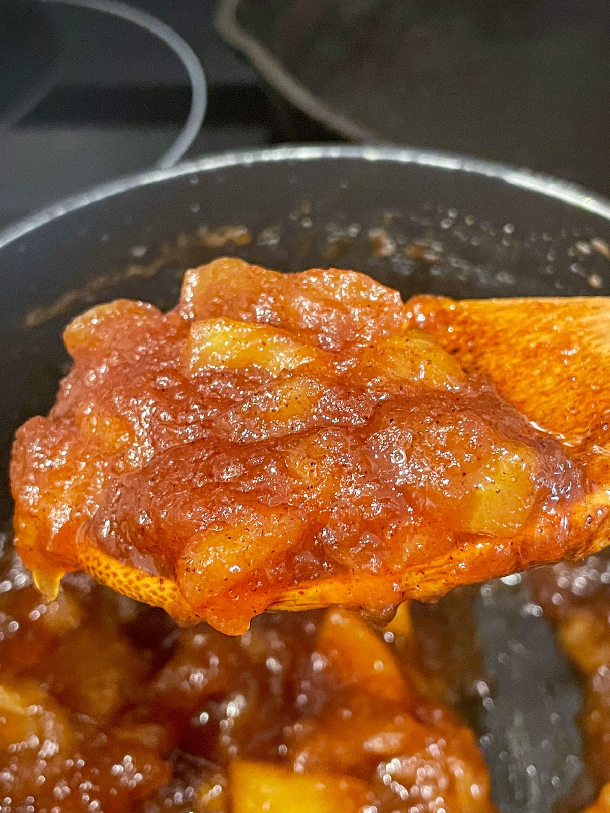 close up shot of thickens apple jam on a spoon.