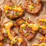 overhead shot of crispy smashed potatoes with creole sauce on parchment paper.