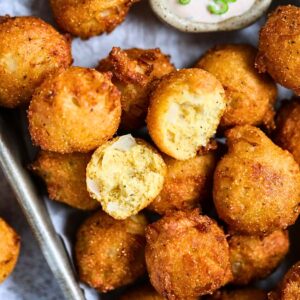 Crispy Southern hush puppies in a metal serving platter.