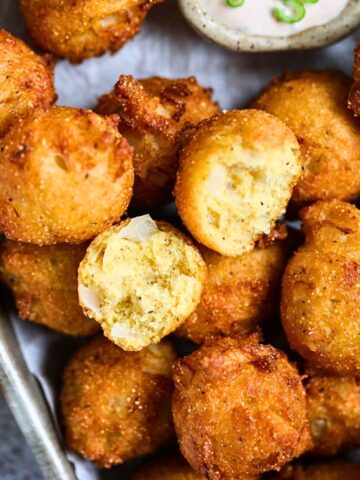 Crispy Southern hush puppies in a metal serving platter.