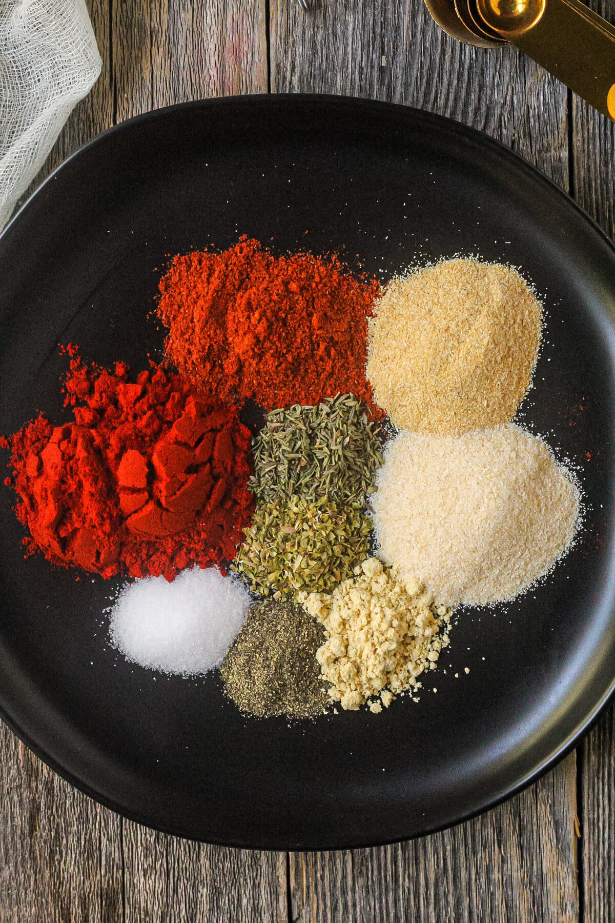 overhead shot of unmixed spices for blackning seasoning on a black plate.