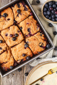 blueberry butter swim biscuits in a metal baking pan on a wooden surface.