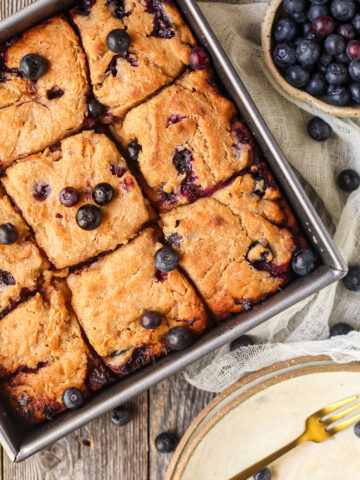 blueberry butter swim biscuits in a metal baking pan on a wooden surface.