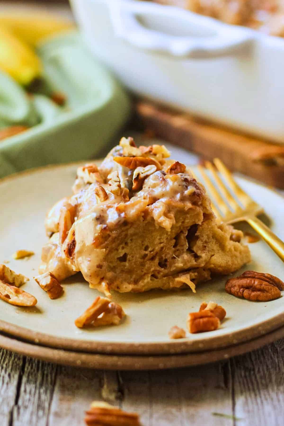 Hummingbird bread pudding with praline sauce on a gray plate with a gold fork.