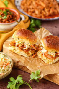 Barbecue pulled chicken sliders with southern coleslaw on a wooden cutting board