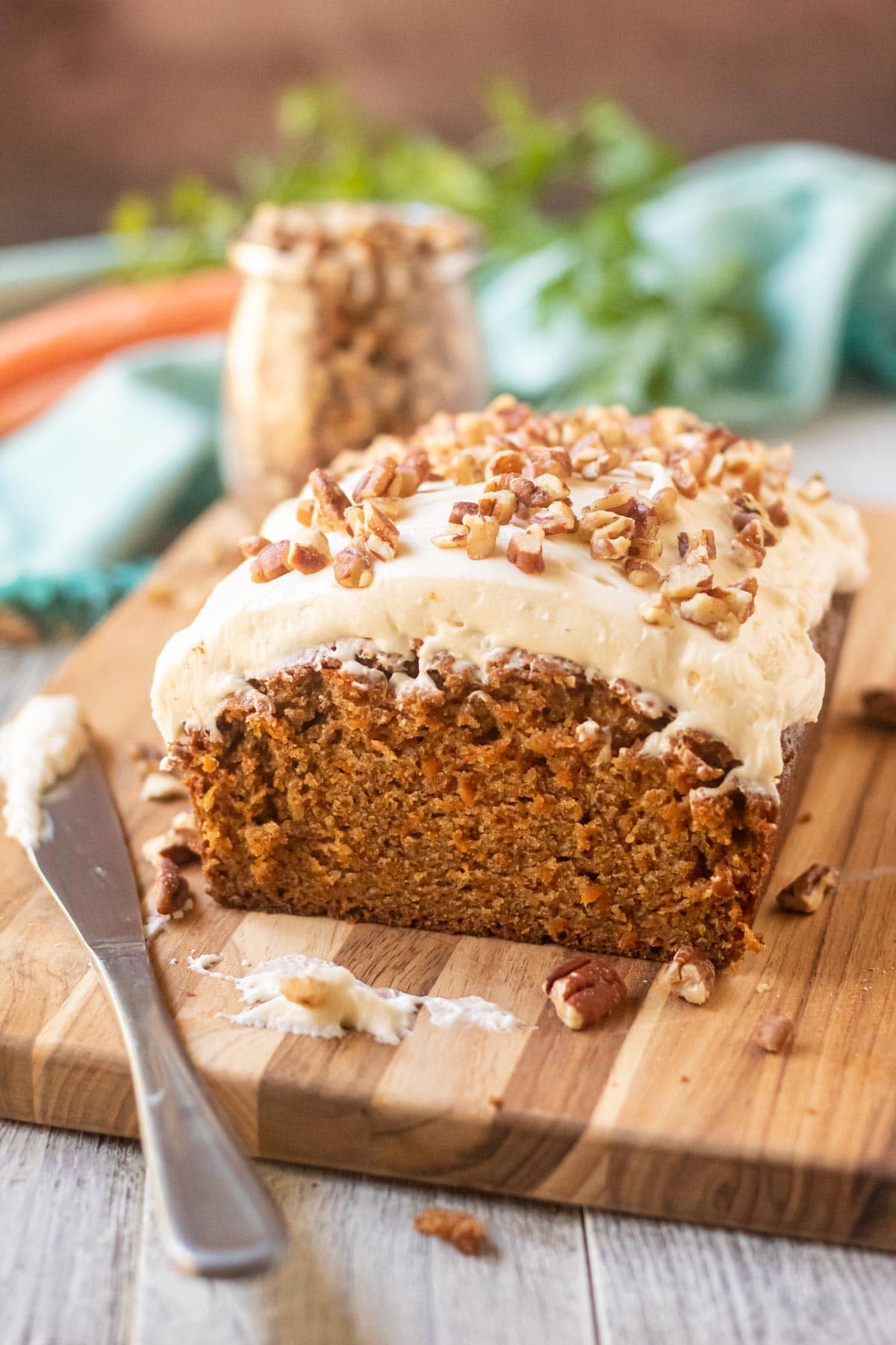carrot loaf cake with cream cheese frosting on wooden cutting board