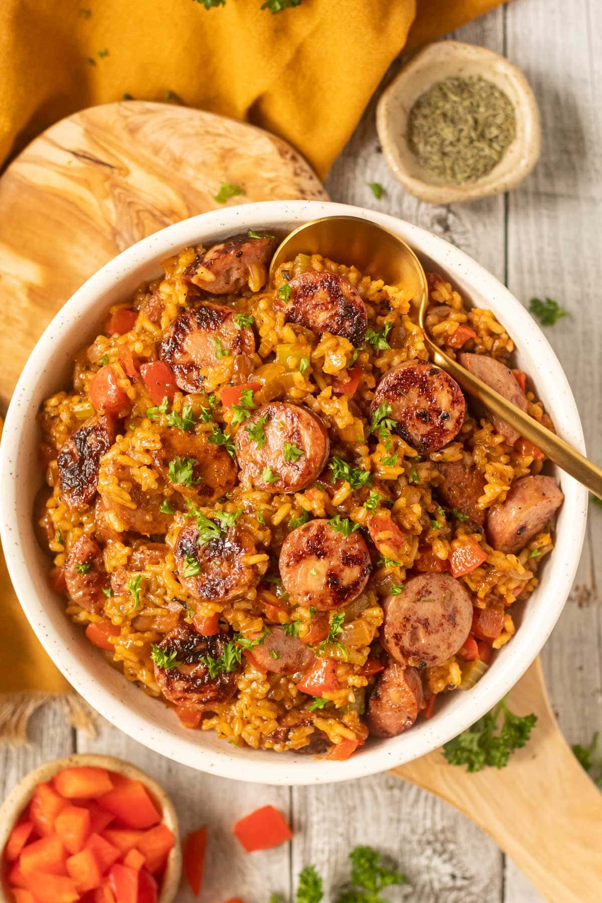 cajun dirty rice with smoked sausage in a white bowl on a wooden cutting board.