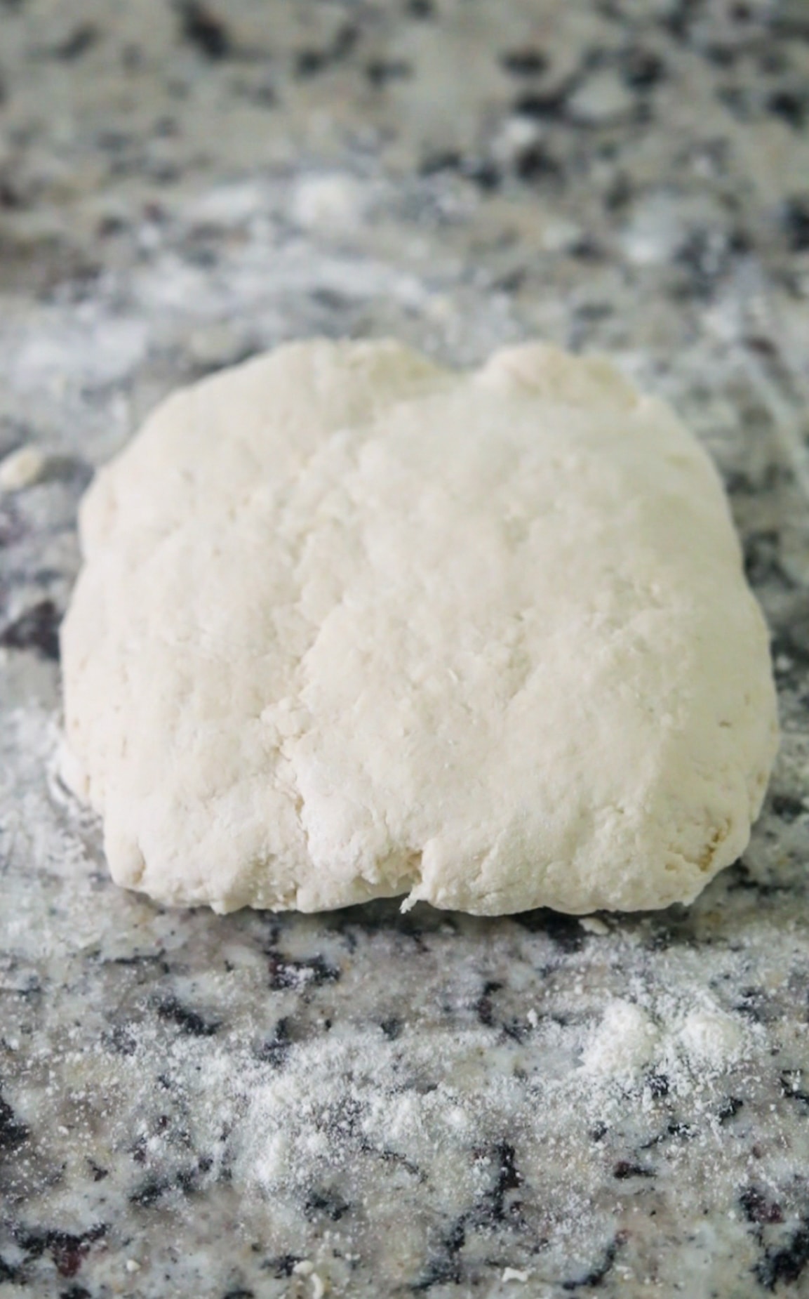 sour cream biscuit dough patted into a rectangle on a countertop.
