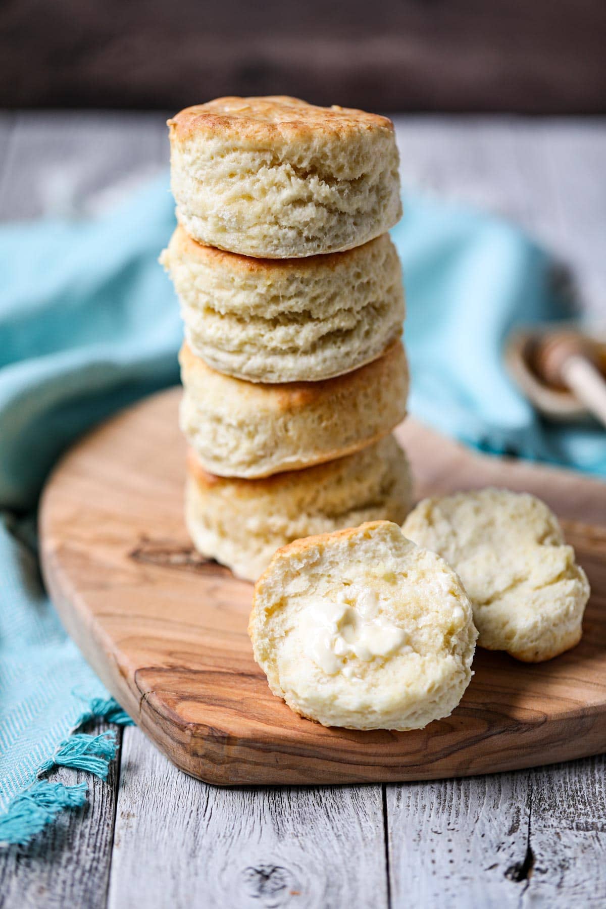 sour cream biscuits stacked on a wooden cutting board.
