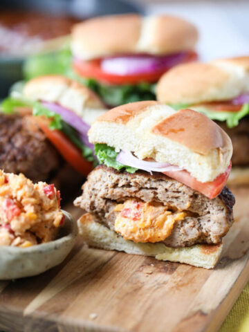grilled pimento cheese stuffed burgers on a wooden cutting board.