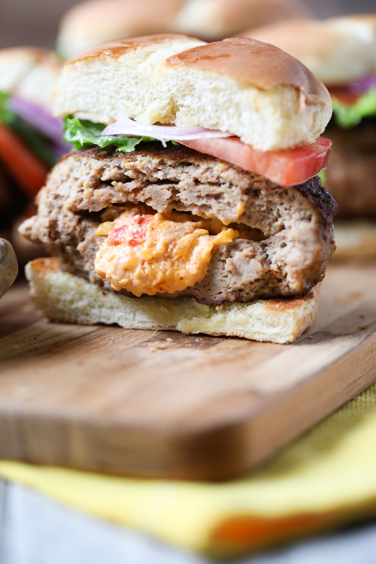 grilled pimento cheese stuffed burger cut in half on a wooden cutting board.