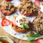 maple grilled peaches with granola topping and vanilla ice cream on a wooden cutting board.