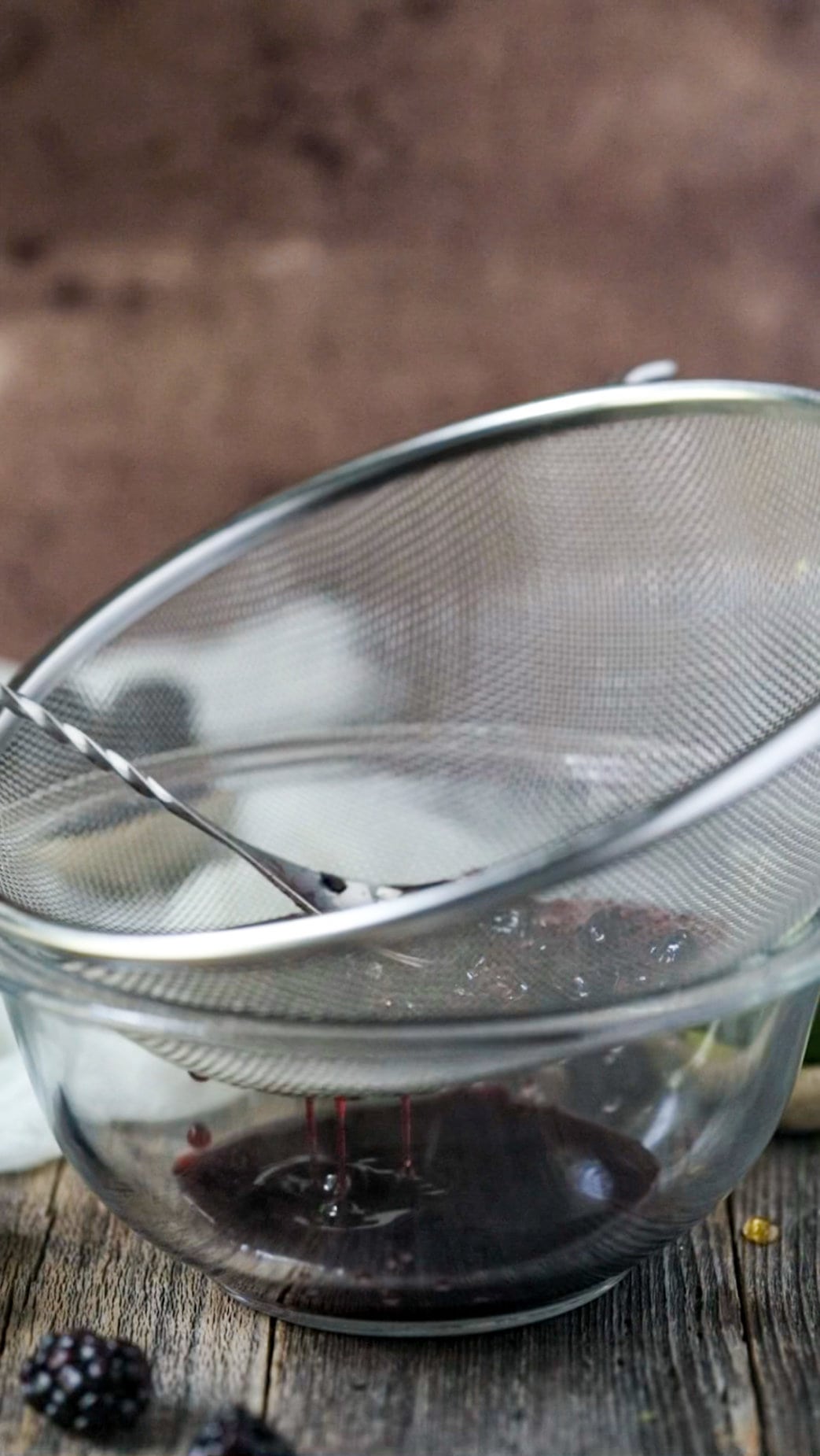 blackberry syrup passing through mesh strainer.