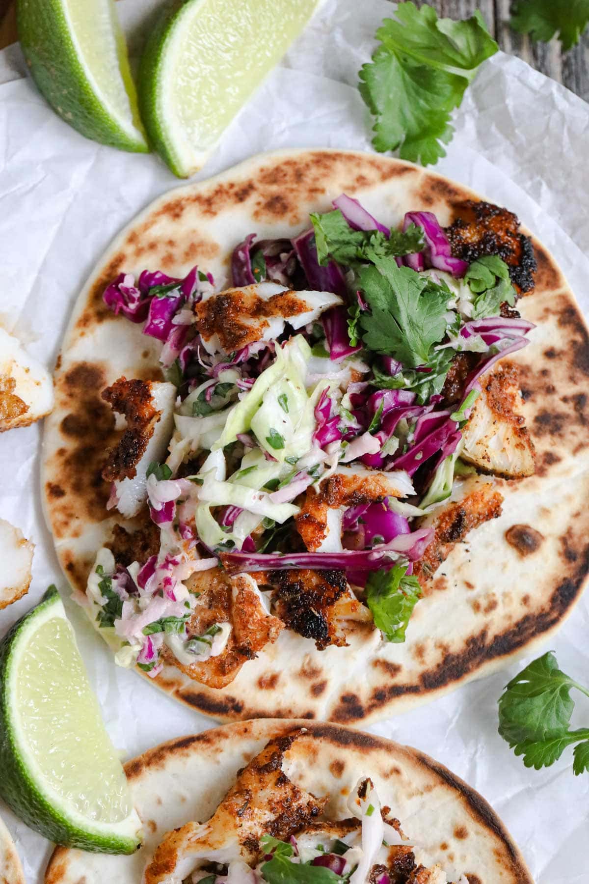 blackened redfish tacos with slaw on a wood cutting board.