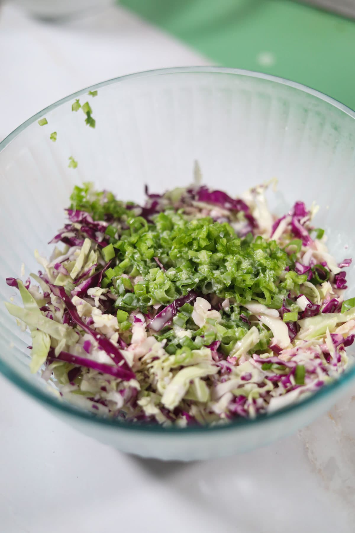 cabbage and herbs for slaw in a clear mixing bowl.