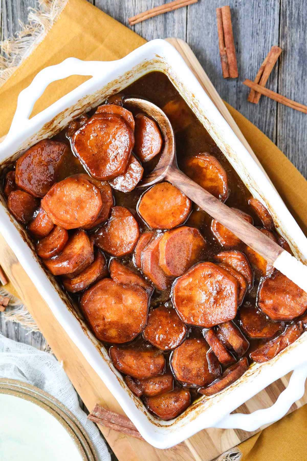 southern candied yams in a baking dish on a wooden surface.